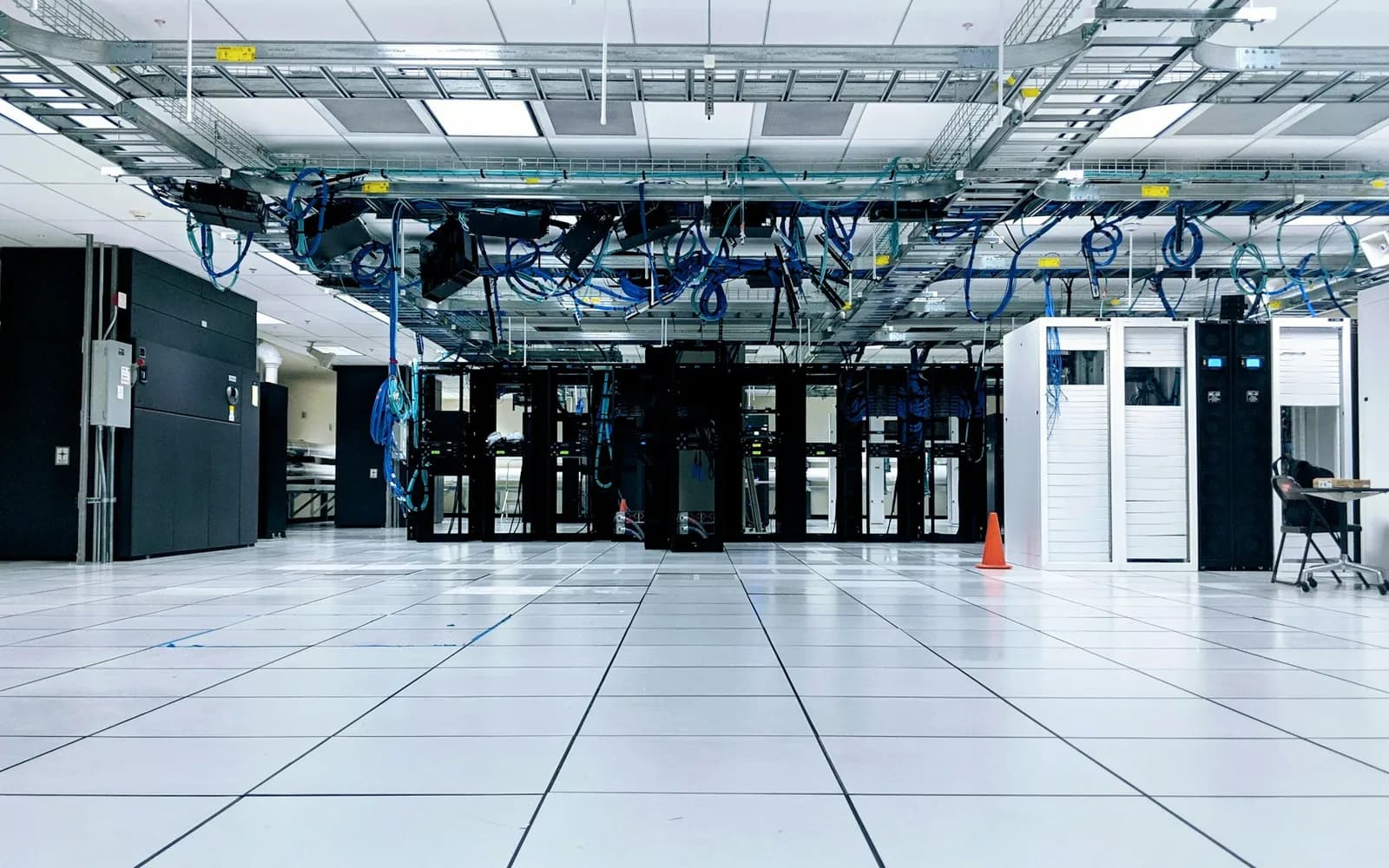 A data centre hall with rows of server cabinets and overhead cable trays